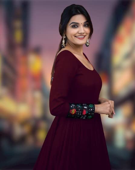 Smiling woman wearing maroon solid pattern stitched gown for women with embroidered cuff sleeves and earrings