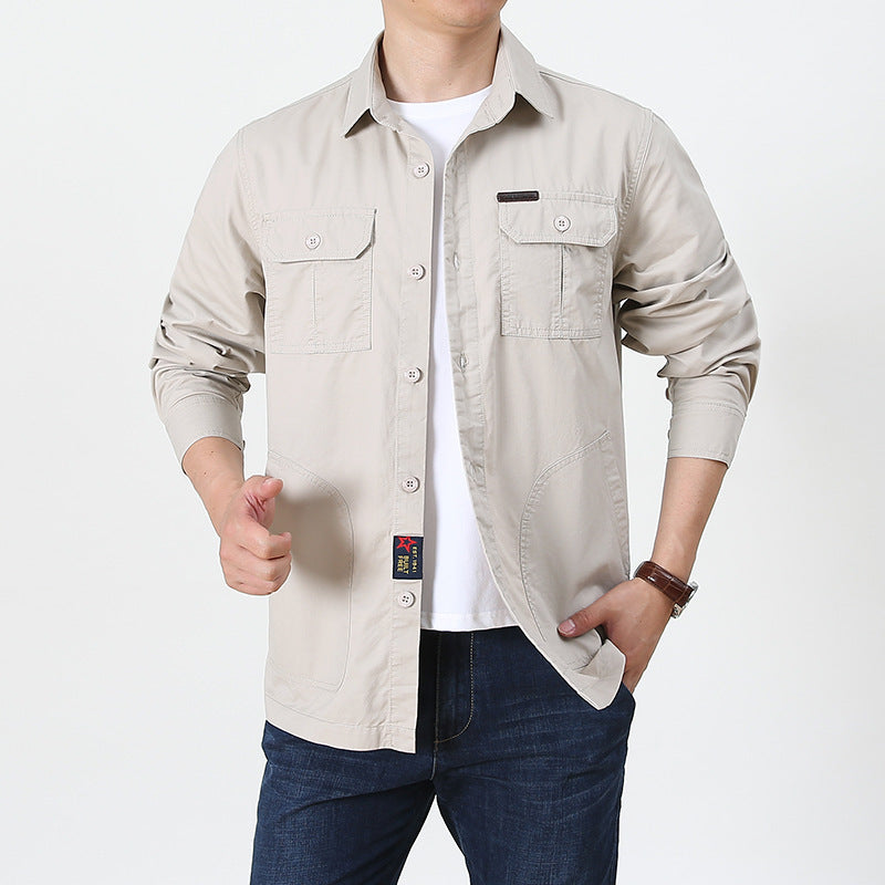 Beige mens lightweight button up shirt with chest pockets long sleeves worn over white tee and jeans