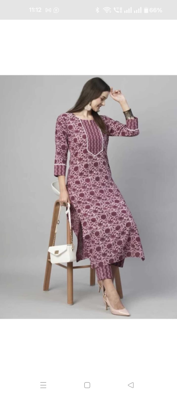 Model wearing maroon printed floral cotton kurta set for women with matching pants three quarter sleeves and white handbag