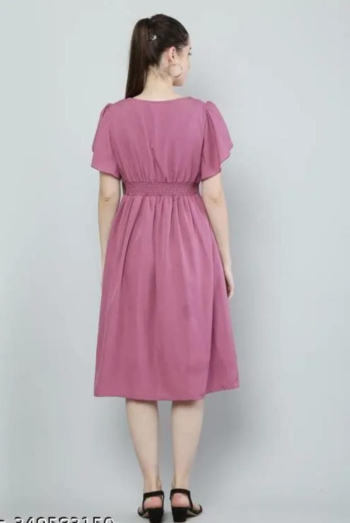 Back view of model in a knee length pink fit and flare dress for women with shirred waist and flutter sleeves