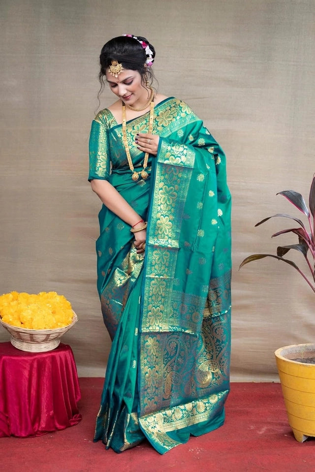 Model wearing Banarasi silk saree royal blue label shown in teal green with gold zari motifs and intricate pallu for weddings