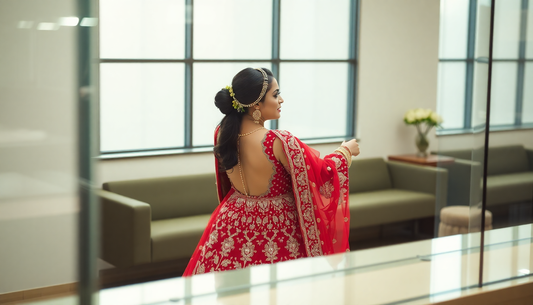 Woman dressed in a red lehenga with floral embroidery learning how to shop for lehengas online