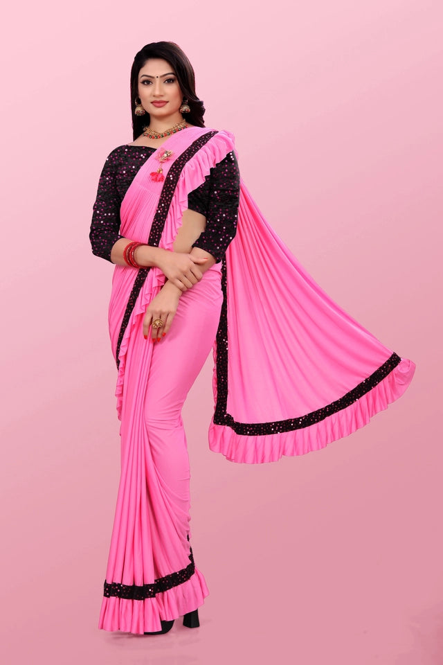 Woman wearing an affordable party wear saree for women in pink with black embellished border and ruffles