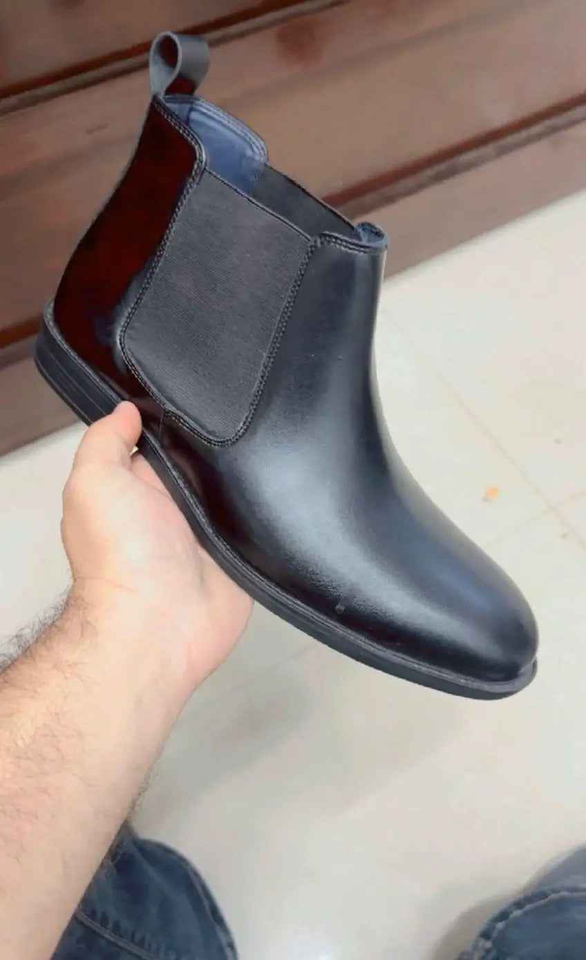 Black slip on boots for men featuring smooth leather finish and elastic side panels for easy wear