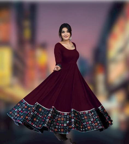 Woman in maroon twirling full skirted gown with colorful hem border solid pattern stitched gown for women