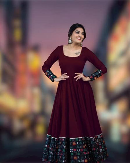 Maroon ankle length dress with patterned hem and cuffs worn by smiling model solid pattern stitched gown for women