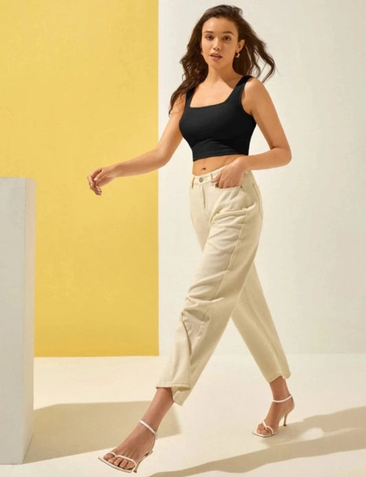 Model wearing black cotton blend top for women with high waisted cream trousers and white heels