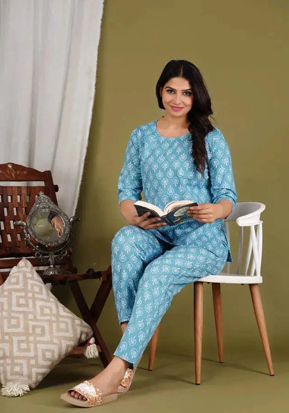 Woman wearing blue floral print co ord set kurti sitting on white chair reading a book
