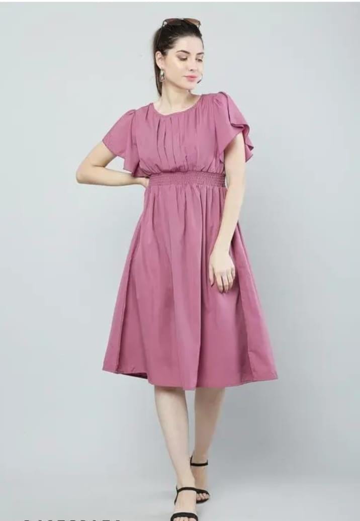 Woman modeling a pink fit and flare dress for women with smocked waist flutter sleeves and knee length hem