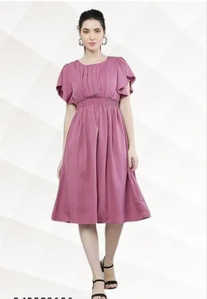 Model wearing a knee length pink fit and flare dress for women with smocked waist flutter sleeves pleated bodice