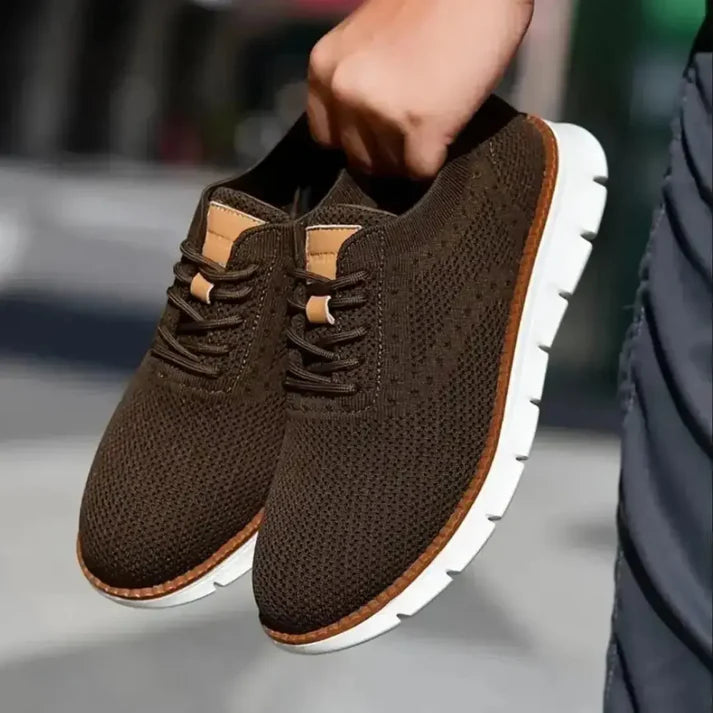 Brown mesh casual shoes for men with white soles and lace-up design held by hand